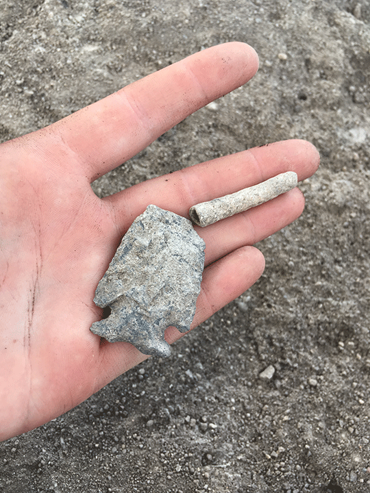 Bone tube and projectile point buried in a sealed floor pit in a Los Pozos pit structure. The projectile point style is older than the house, and was probably already an heirloom or artifact when it was buried.