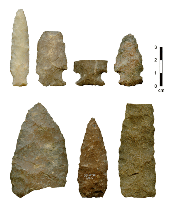 Photo of four San Pedro phase projectile points and three bifaces from the Milagro site in the eastern Tucson Basin. The points are side notched. The bifaces range from broad and triangular to narrow and rectangular.