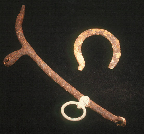 Photo of a horseshoe and iron hame (it attached to the horse collar so cart traces could run through it)