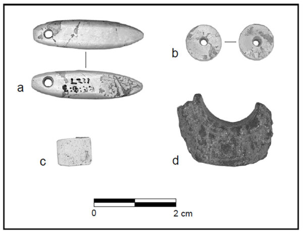 Ground stone ornaments from Fairbank, including a long, narrow oval pendant, a round bead with a central hole, and a ring fragment.