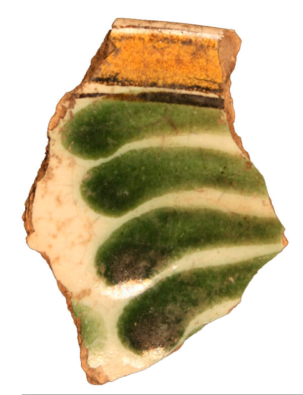 Photo of a majolica sherd. Four dark green swooshes are painted on a cream background, with a orange band at the top.