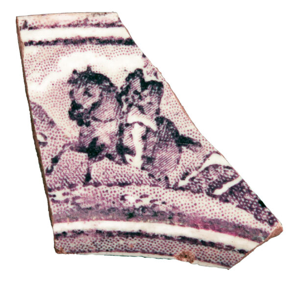 Photo of a purple transferprint sherd. Thisis a fragment of a dish with a purple print of a horseback rider, made of purple dots.
